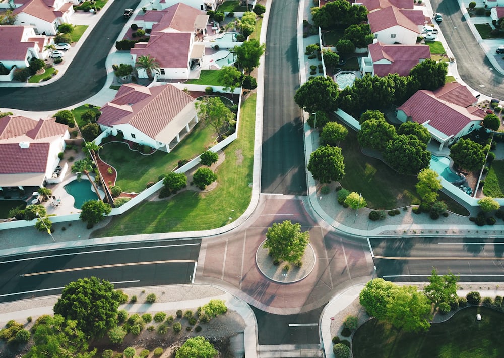 Aerial view of a single-family HOA with tile-roofed homes, pools, and tree-lined streets.